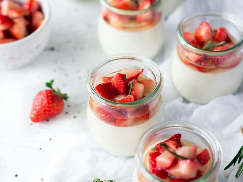 Postres de crema en frascos de vidrio coronados con frutillas frescas