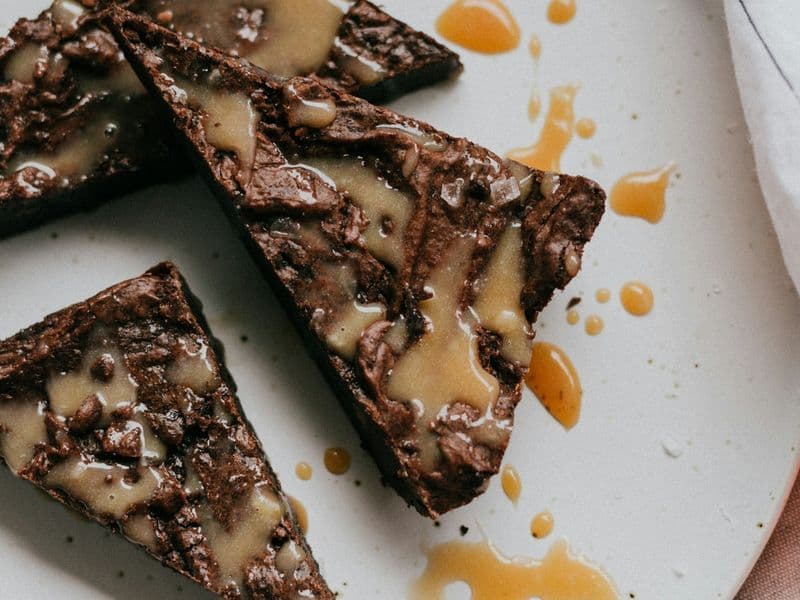 Tres porciones de brownie con caramelo salado servidas en un plato blanco