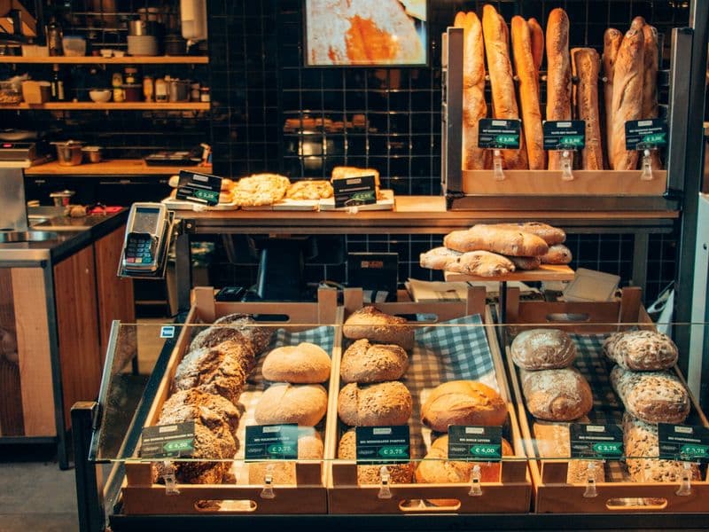 Vitrina de panadería con panes artesanales y baguettes en bandejas de madera